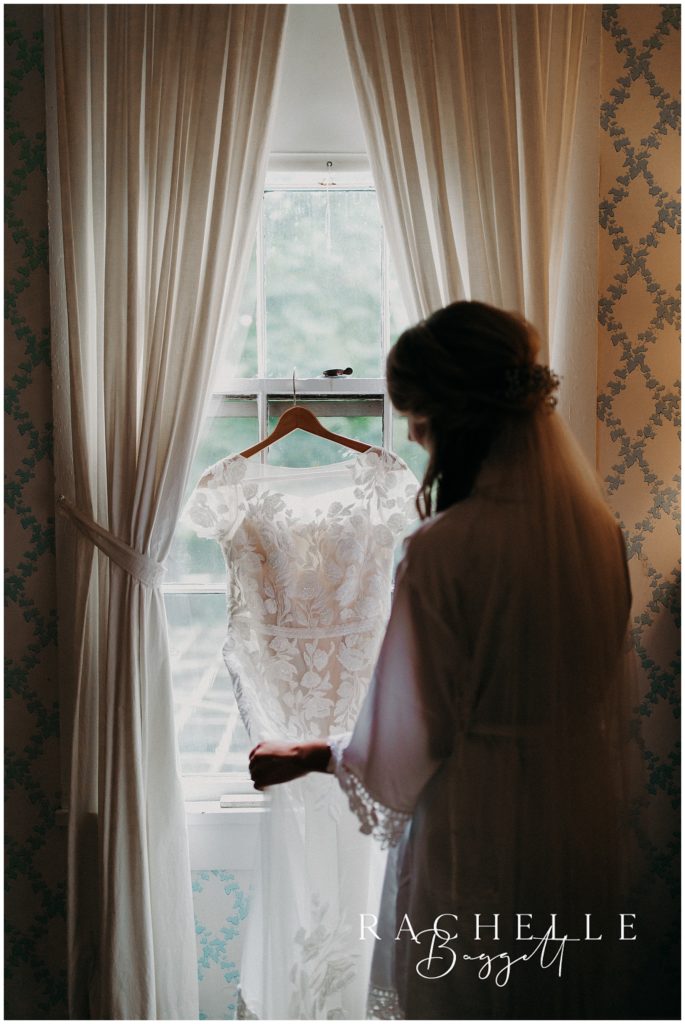 bride holds dress in window