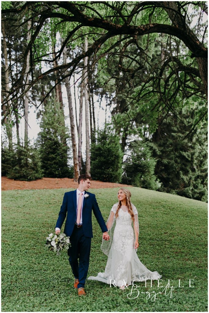 bride and groom walk through field