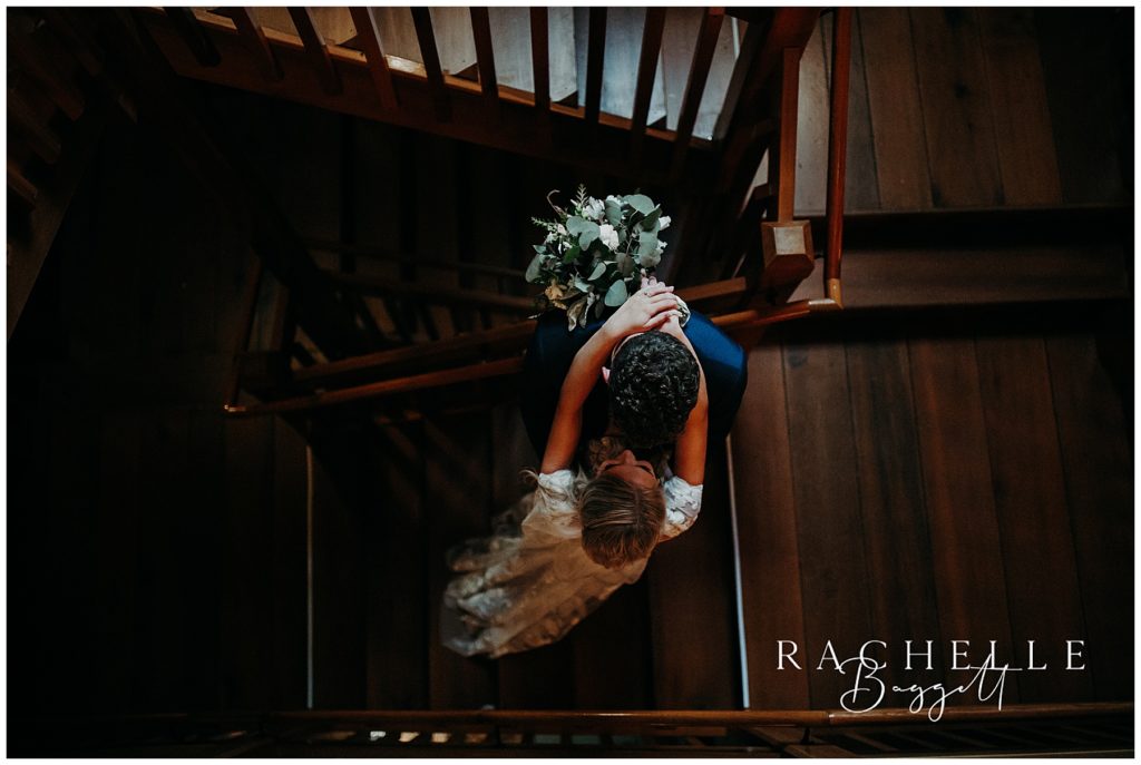 bride and groom stand on stairs and kiss