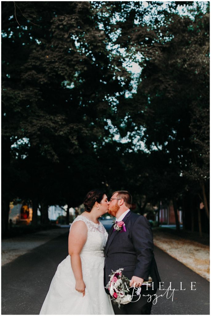 A bride and groom kissing in the street outside of The Granary in New Harmony, Indiana