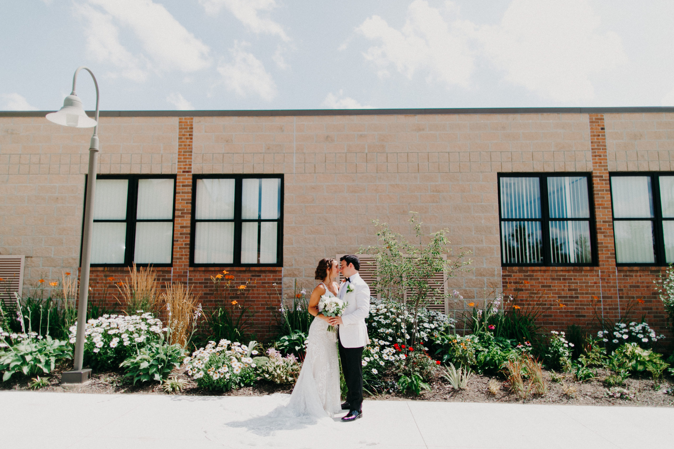 a bride and groom kiss outside of st. Joseph Catholic Church in brighton, michigan