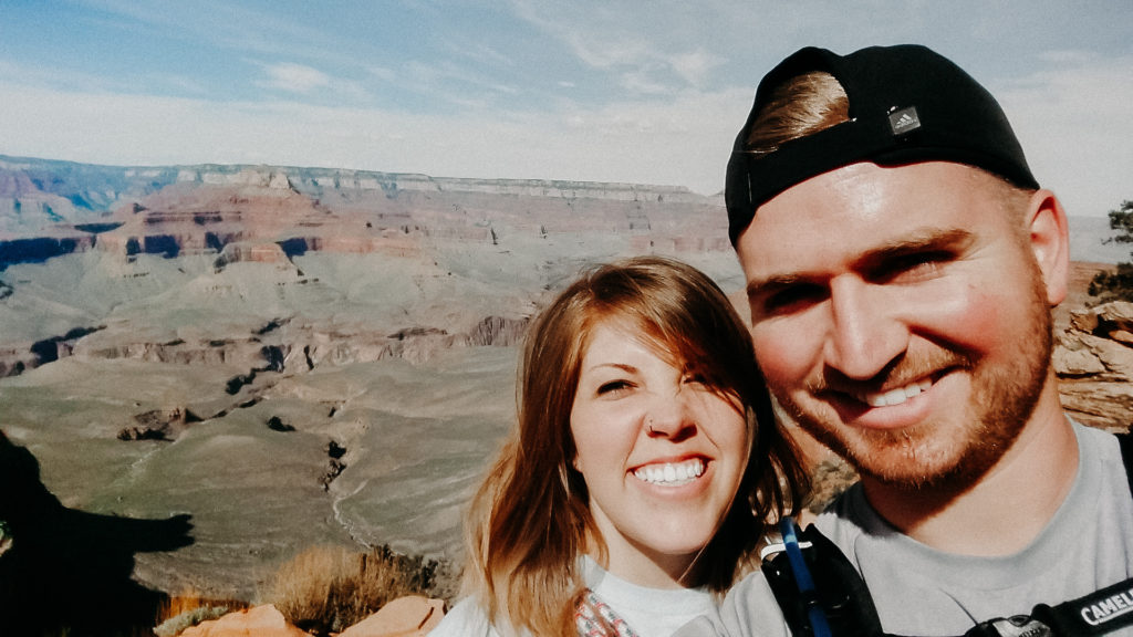 man and woman smile at grand canyon