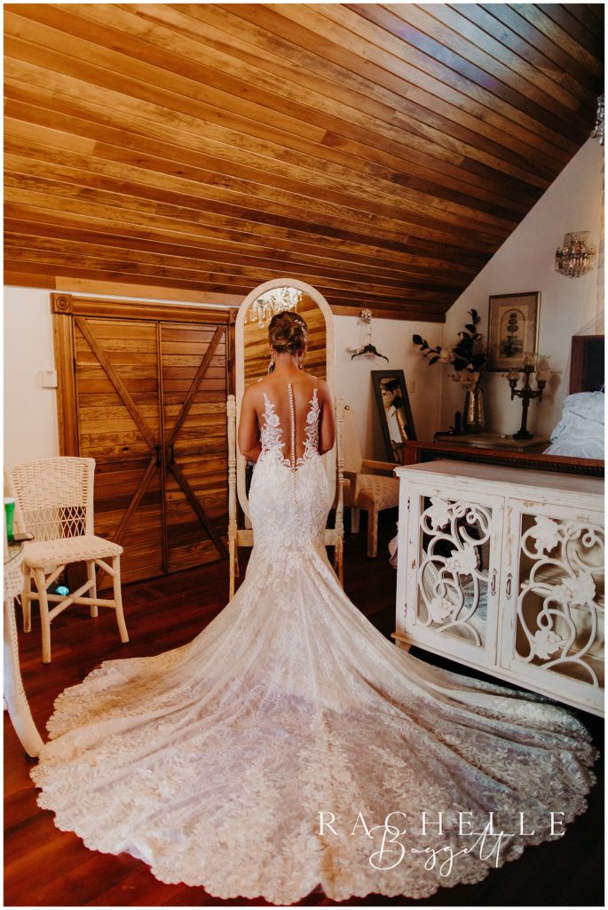 a woman in a wedding dress standing in front of mirror. 