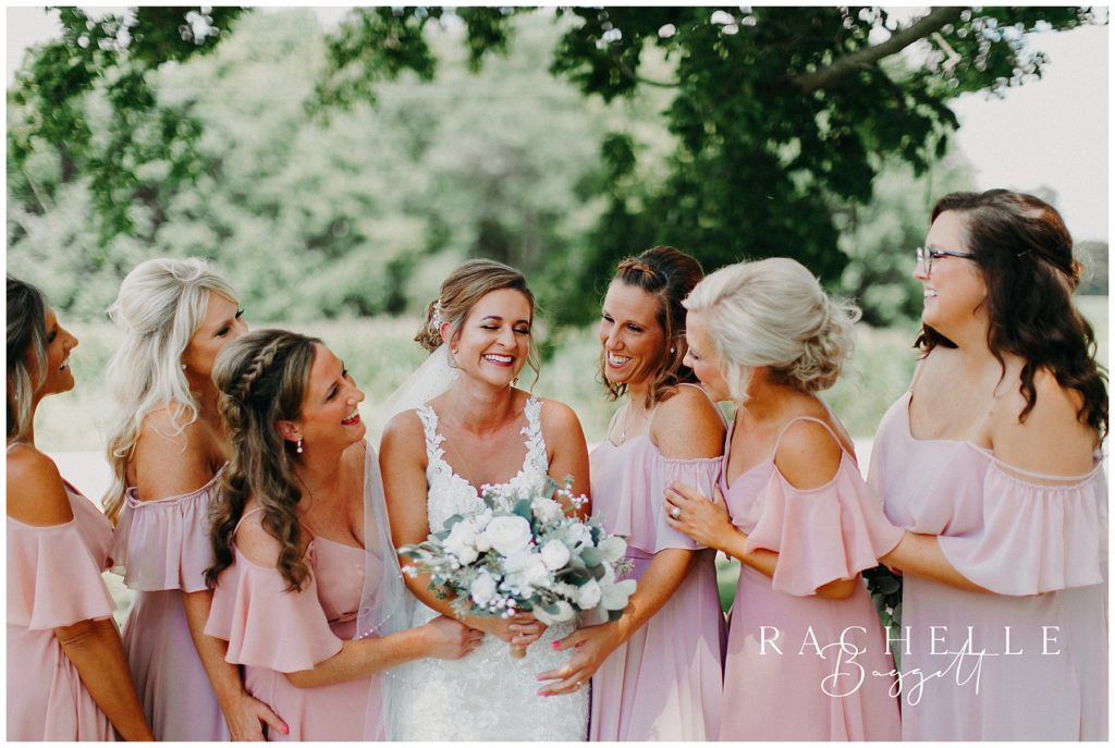 a bride and her bridesmaids smile at each other . Evansville Wedding Photographer.