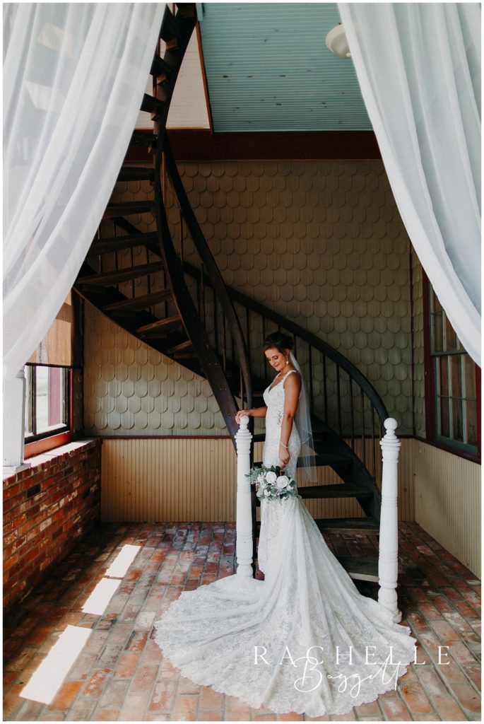 a bride stands on a staircase and smiles while holding flowers. Evansville Wedding Photographer.