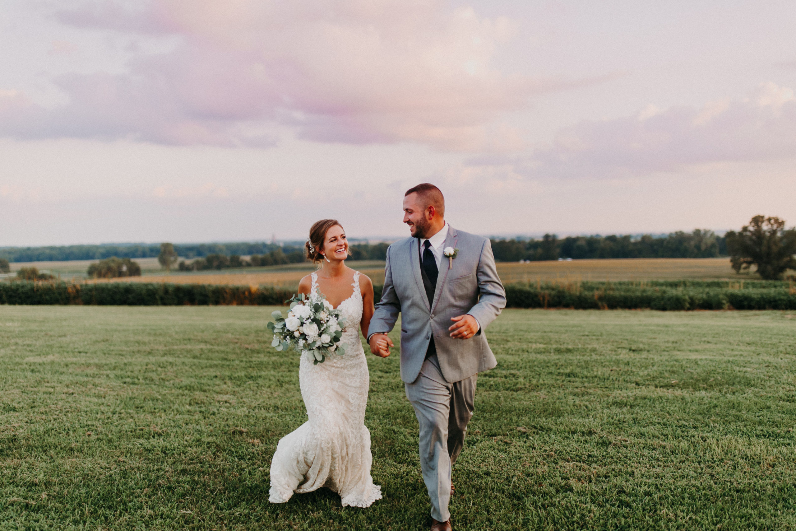 groom and bride smile and run in field