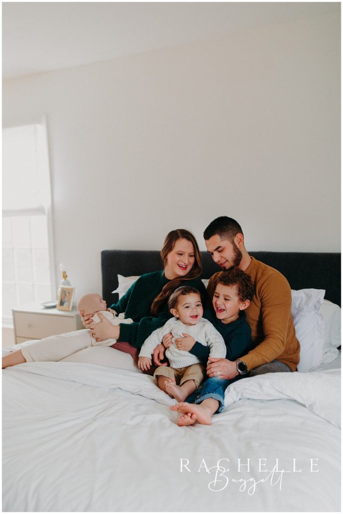 Man and woman snuggle with their three children in cozy in-home family session