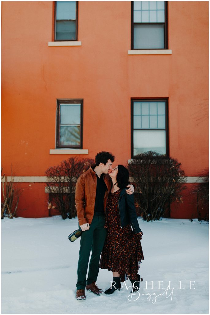 husband and wife lean in for a kiss in the snow during anniversary session