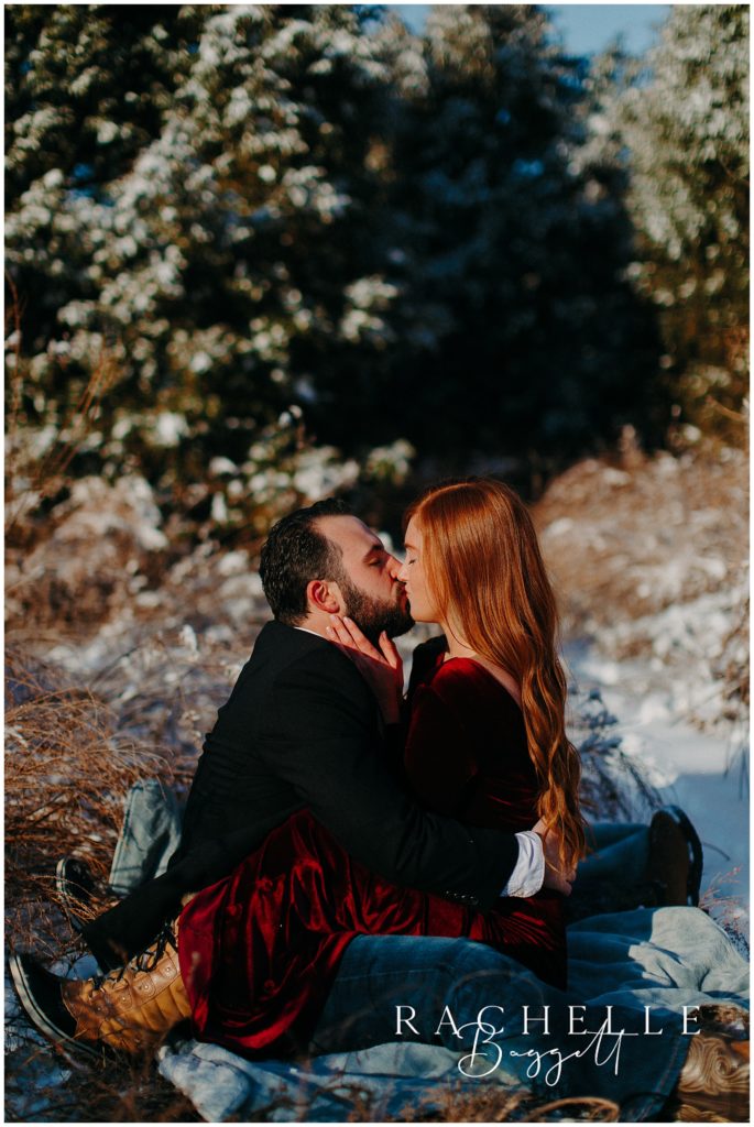 engaged couple share a kiss during their snowy sunrise engagement session