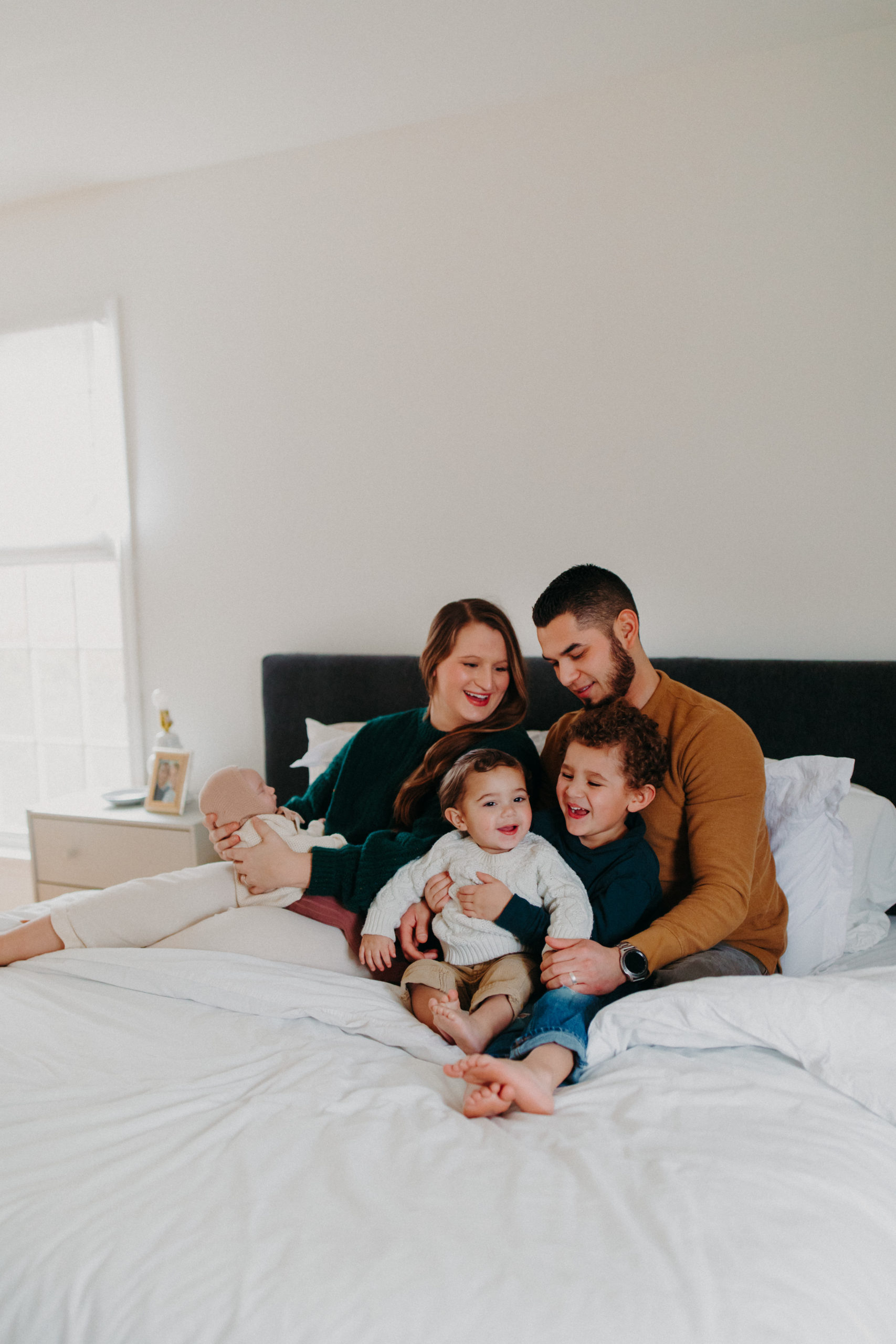 man and woman sit on bed with their children
