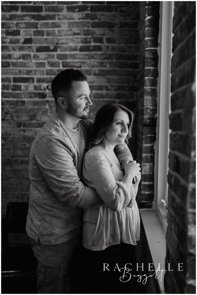 man and woman gaze outside window during Downtown Loft Couples Session