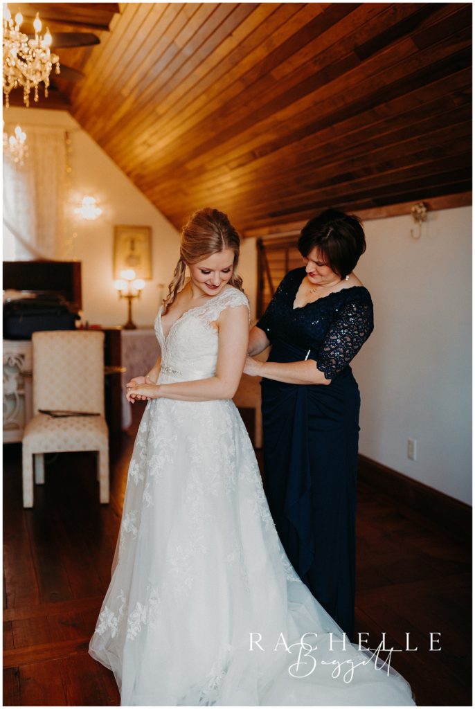 mother helping bride into dress