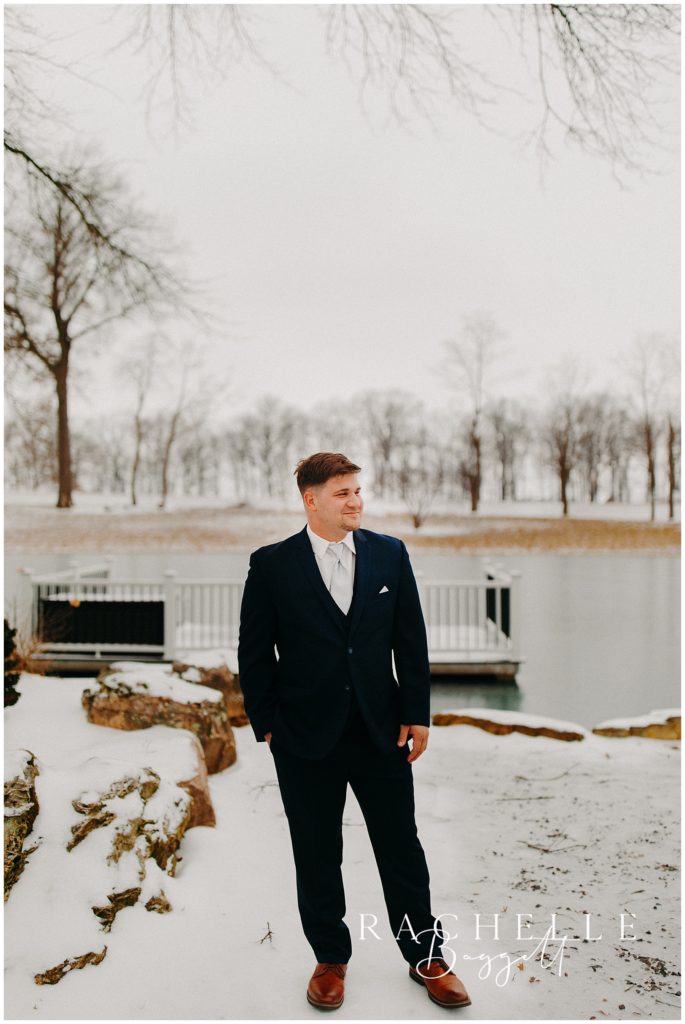 groom posing by lake