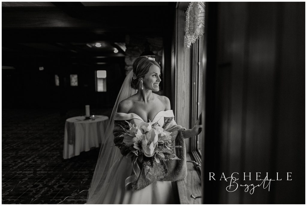 black and white photo of bride looking out window
