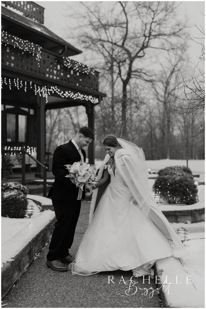 groom helps bride walk through the snow