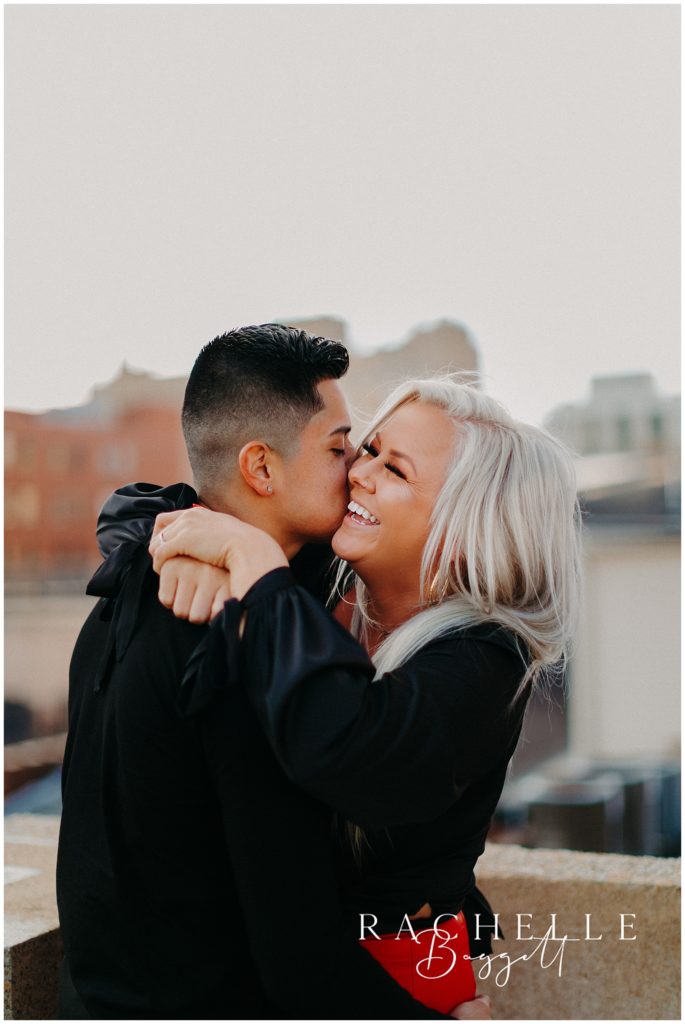 man and woman embrace during rooftop engagement session