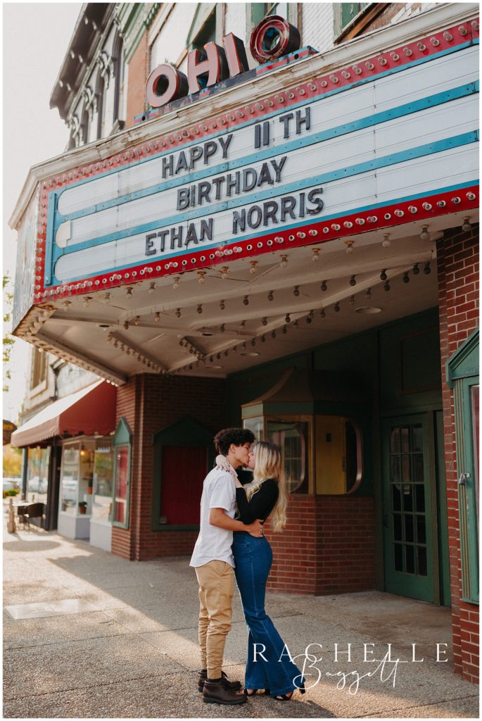 engaged couple kisses under old movie theatre
