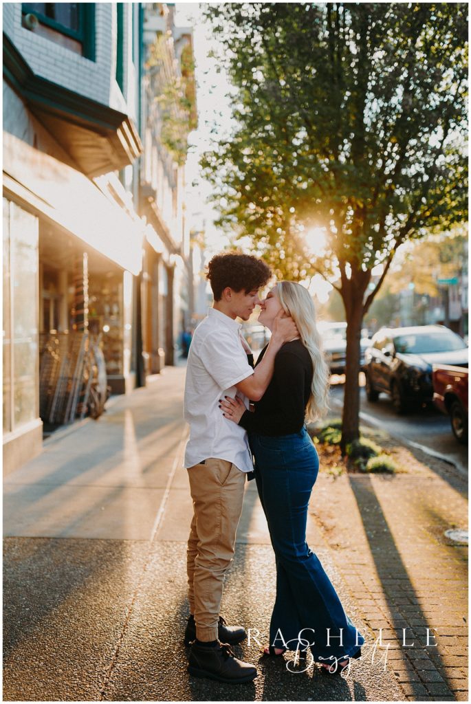 man leans into kiss woman during Engagement in Historic Downtown