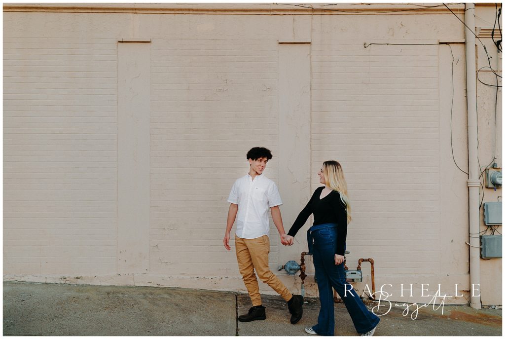 man and woman walk outdoors in historic downtown for engagement session
