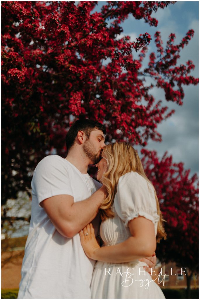 man kisses woman on forehead outside