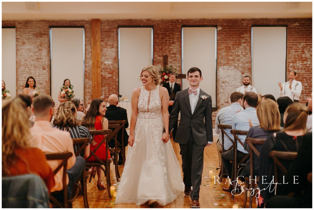 bride and groom walk down the aisle together as one - Spring Wedding at City View