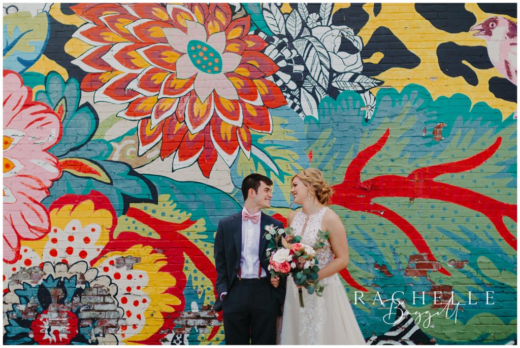husband and wife posing in front of mural