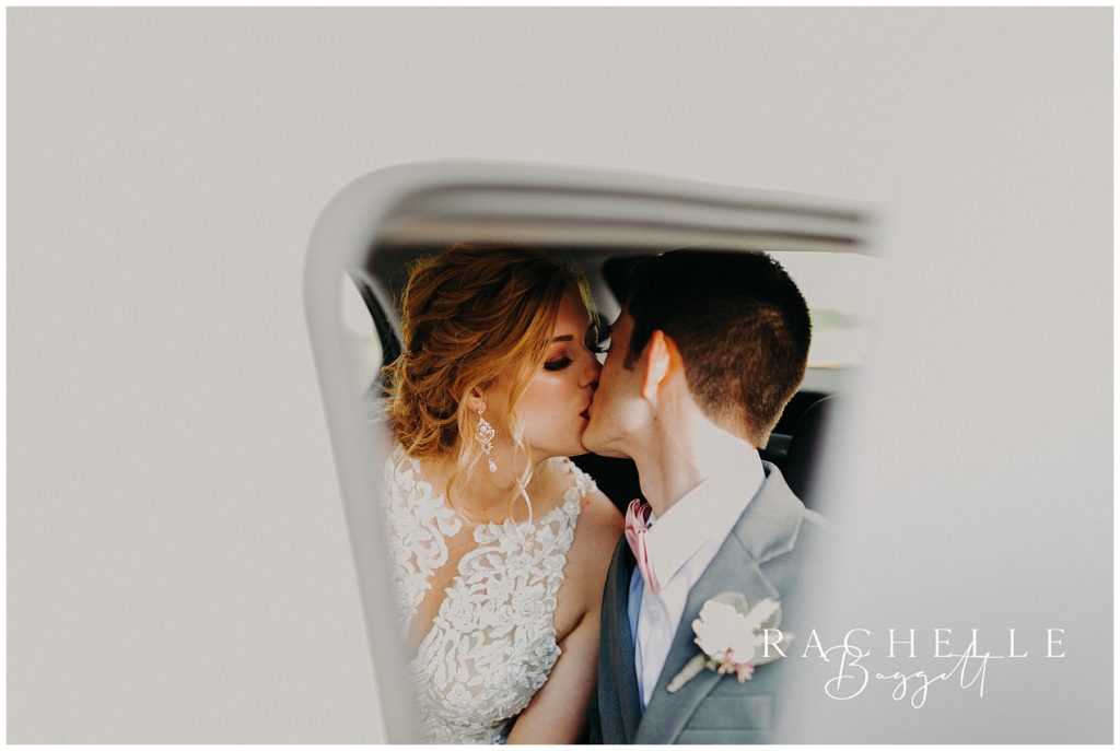 bride and groom kiss in rearview mirror