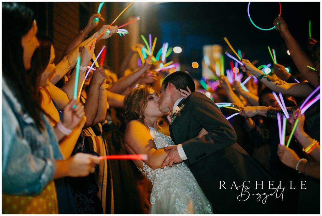husband and wife kiss during Spring Wedding at City View glow stick exit